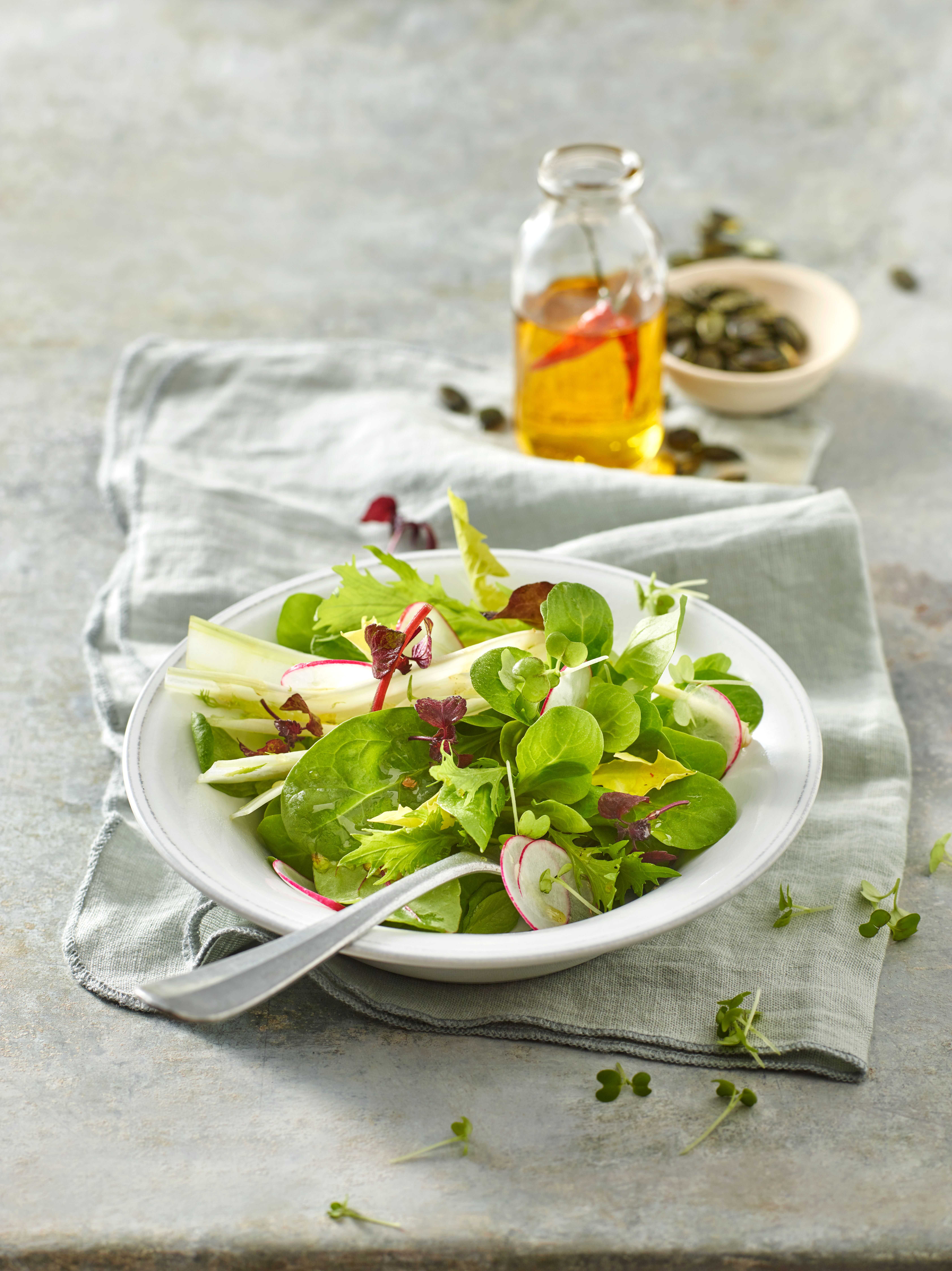 Salat in einer Schale mit Chiliöl daneben