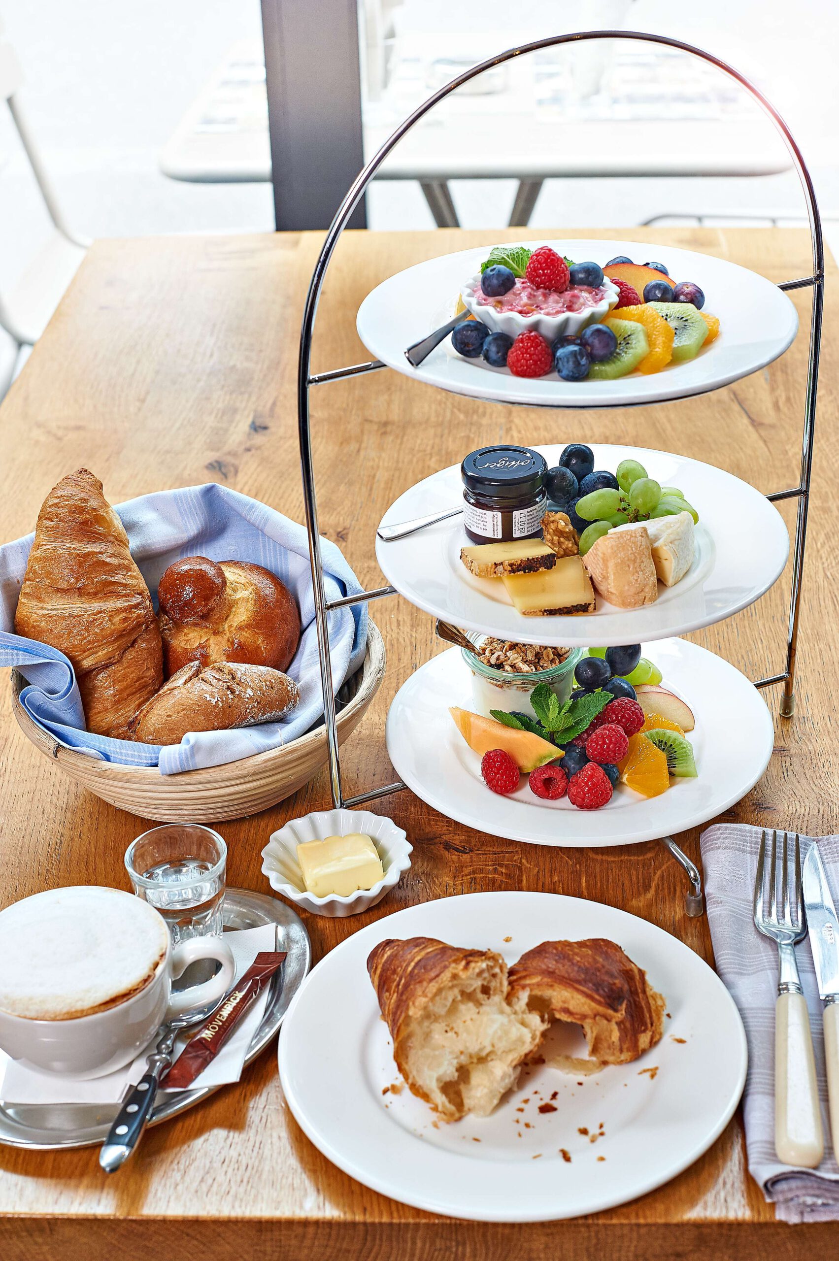 Frühstückansgebot auf einer Etagere mit Obst, Aufschnitt, Croissants und Kaffee